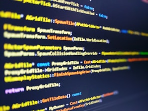 A close-up shot of computer code displayed on a monitor. The code syntax includes keywords and commands typically used in programming, with varying colors like yellow, blue, and white for different elements. The image has a shallow depth of field with the focus on the central portion of the script.