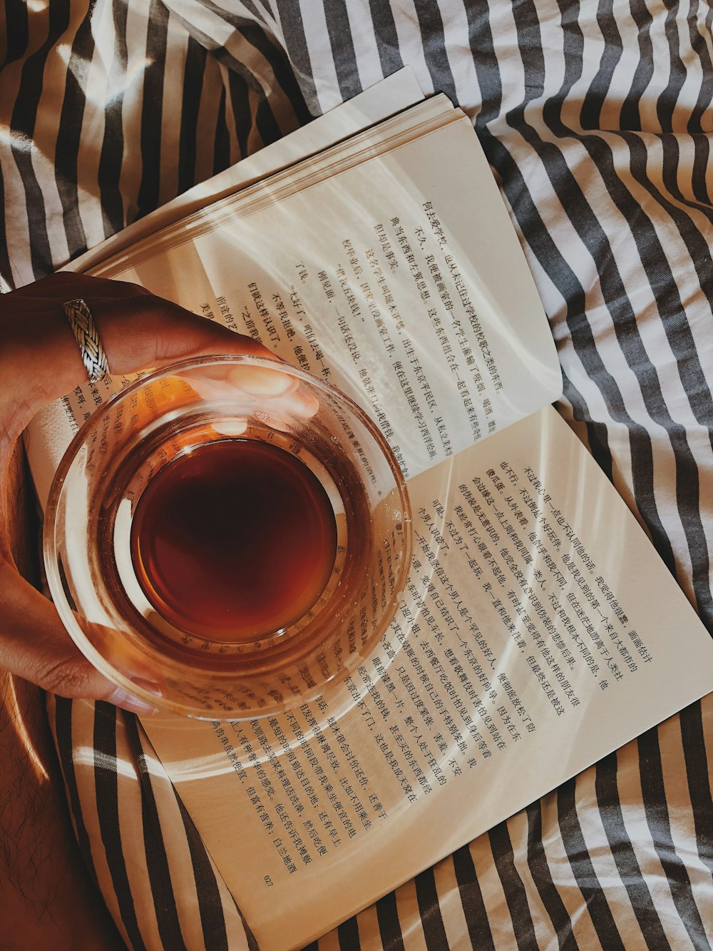 person holding a cup of tea on opened book