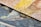 Close-up view of two textured, overlapping canvases displaying vibrant brushstrokes. One canvas features swirling patterns of yellow and beige, while the other showcases a mix of blue and orange tones. The detailed texture of the canvas is visible, highlighting the artistic style.