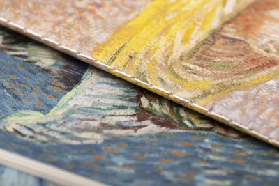 A close-up of a textured canvas showing swirling blue and gold paint.