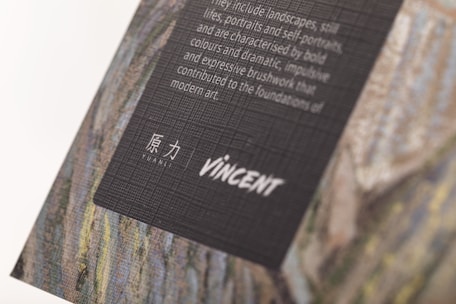 A textured, tilted display of artistic text set on a dark background, featuring a mix of English and Chinese characters. The backdrop appears to be part of a larger artwork, possibly a painting, with visible textured brushstrokes.
