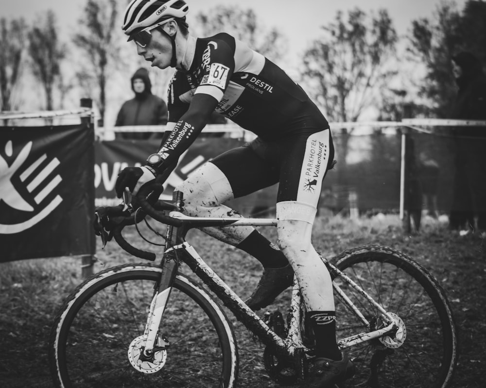 grayscale photo of man riding bicycle