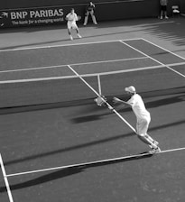 two men playing lawn tennis in grayscale photography