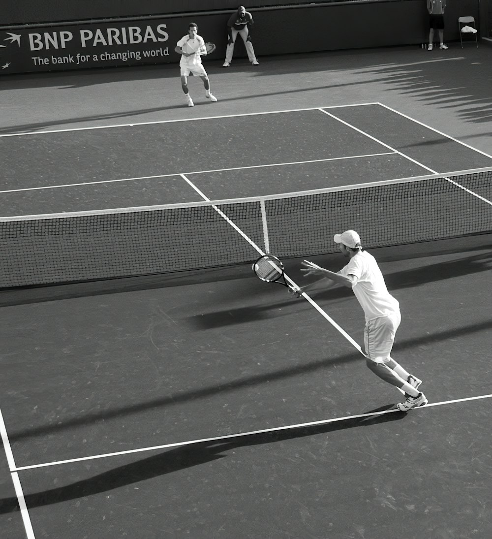 deux hommes jouant au tennis sur gazon dans une photographie en niveaux de gris