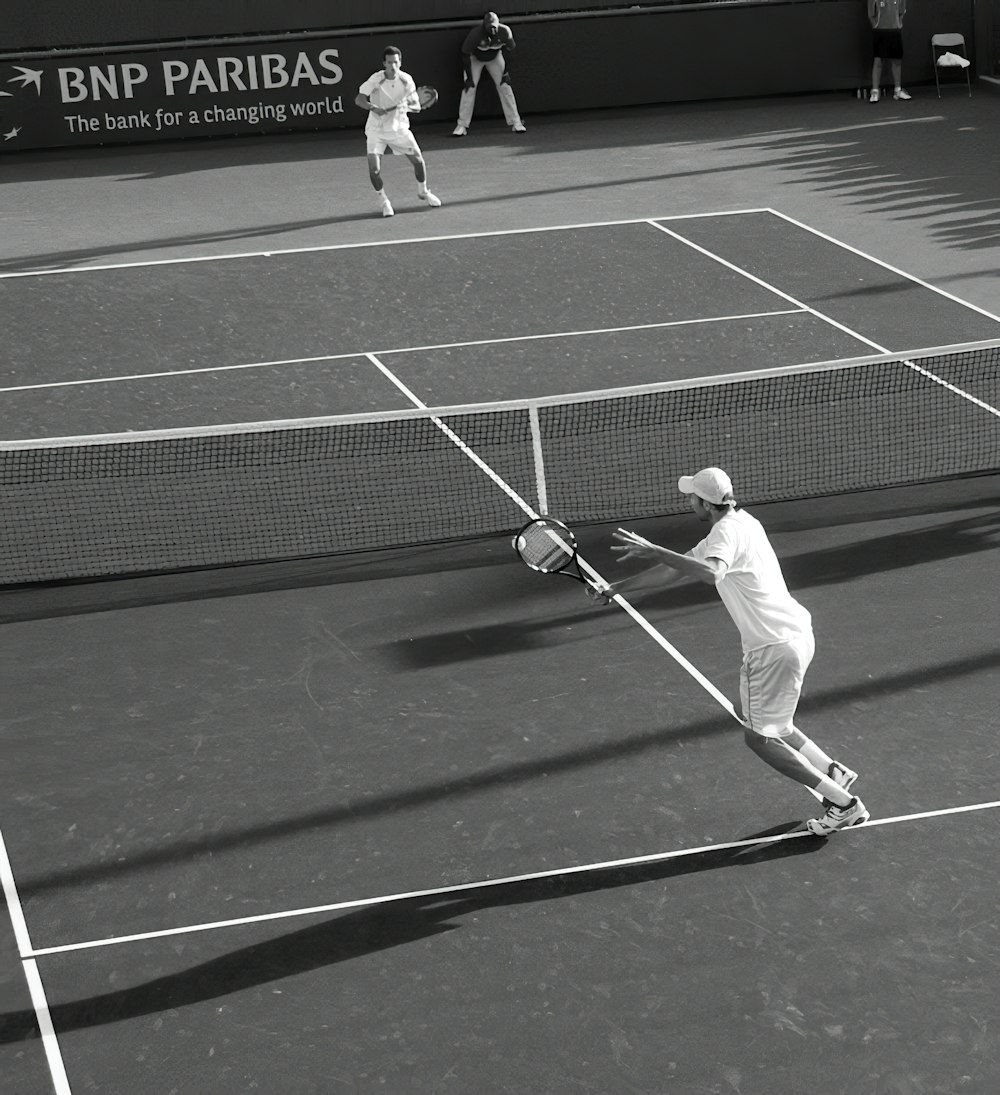 Dos hombres jugando al tenis sobre hierba en fotografía en escala de grises