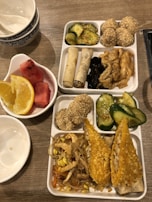 A colorful spread of side dishes and chutneys arranged around a bento box.