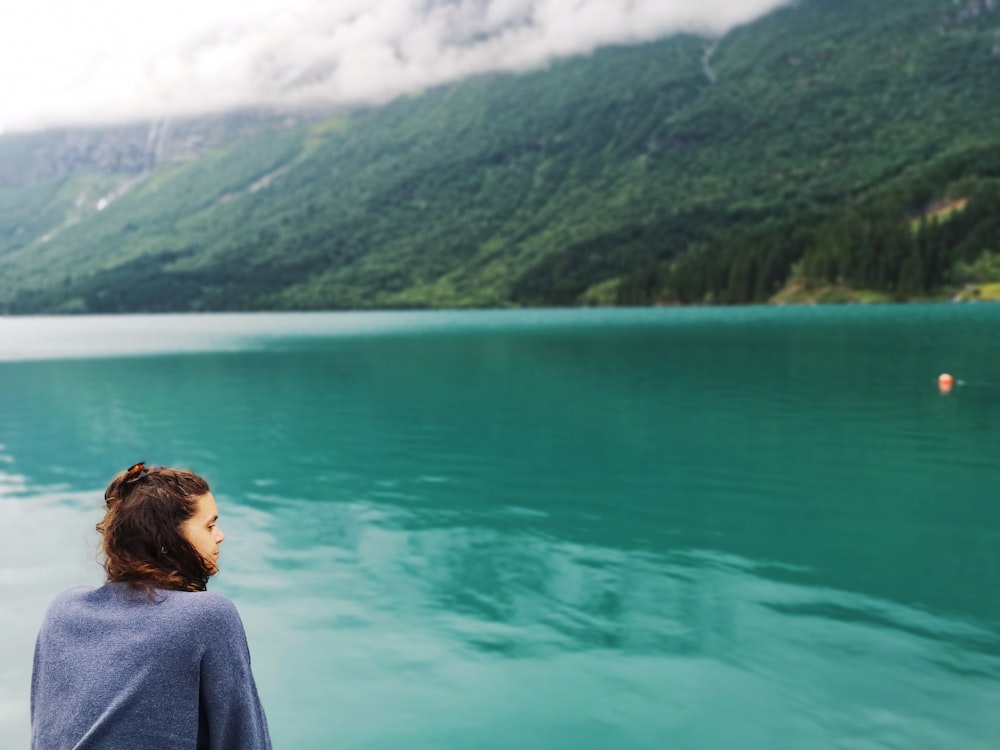 woman in blue sweater beside body of water