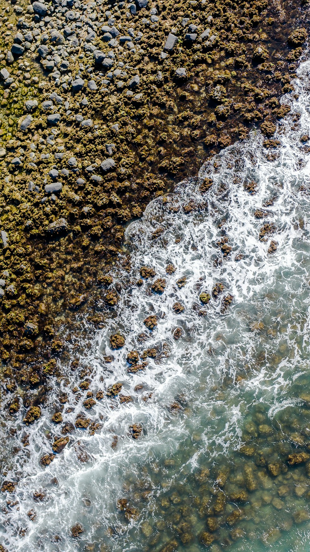 an aerial view of the ocean and rocks