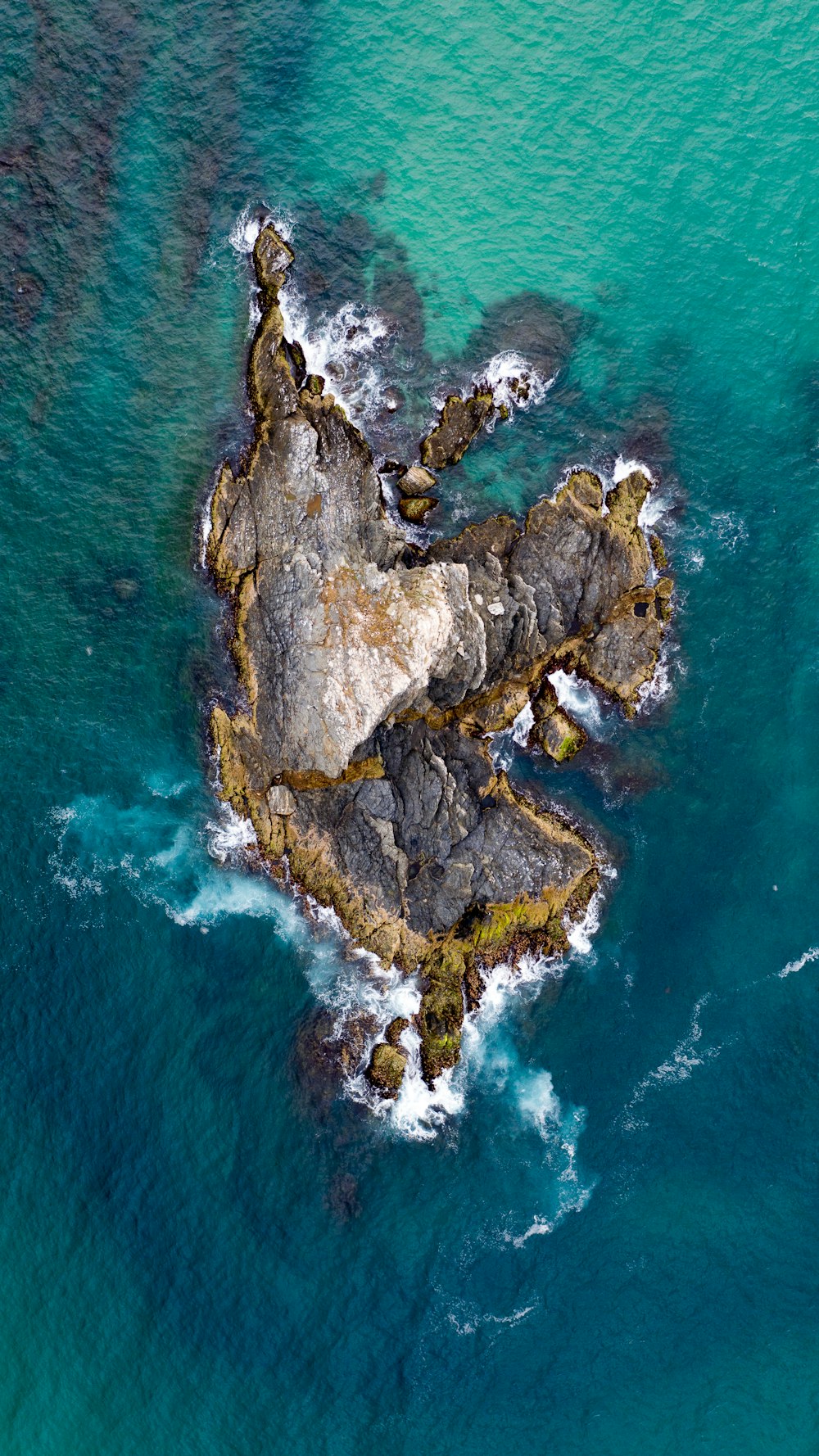 an aerial view of a rock outcropping in the ocean