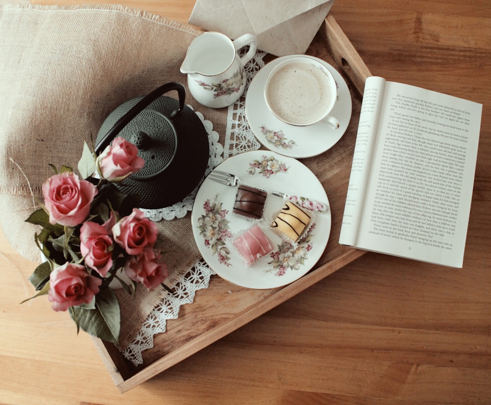 Schwarzer Wasserkocher, Teller, Teetasse und Untertasse auf braunem Tablett