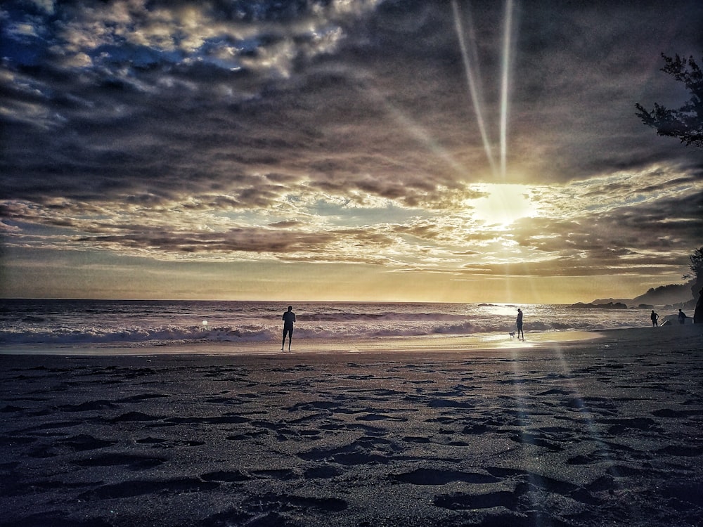 photography of two people standing beside seashore