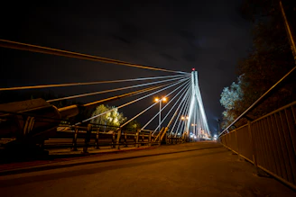 Engineers reviewing plans beside a finished cable-stayed bridge illuminated at dusk.
