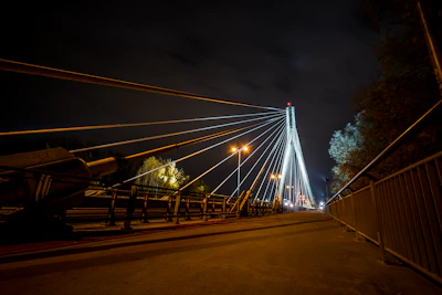 Engineers reviewing plans beside a finished cable-stayed bridge illuminated at dusk.