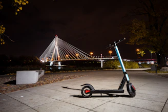 A sleek Sutton electric scooter parked on a city street at sunset