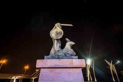 A weathered bronze statue depicting a historic warrior, bathed in soft light.