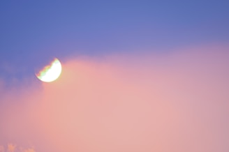 A semi-transparent crescent moon is visible against a gradient sky with hues of blue and pink. The moon appears to be glowing, and there is a faint, dreamy effect where the colors blend softly.