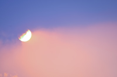 A semi-transparent crescent moon is visible against a gradient sky with hues of blue and pink. The moon appears to be glowing, and there is a faint, dreamy effect where the colors blend softly.