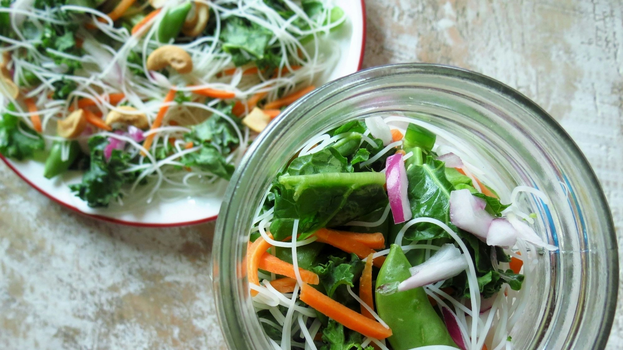 Noodle, veggie and green salad in a mason jar and on a plate. Toss in a smidgen of your favorite teriyaki sauce.
