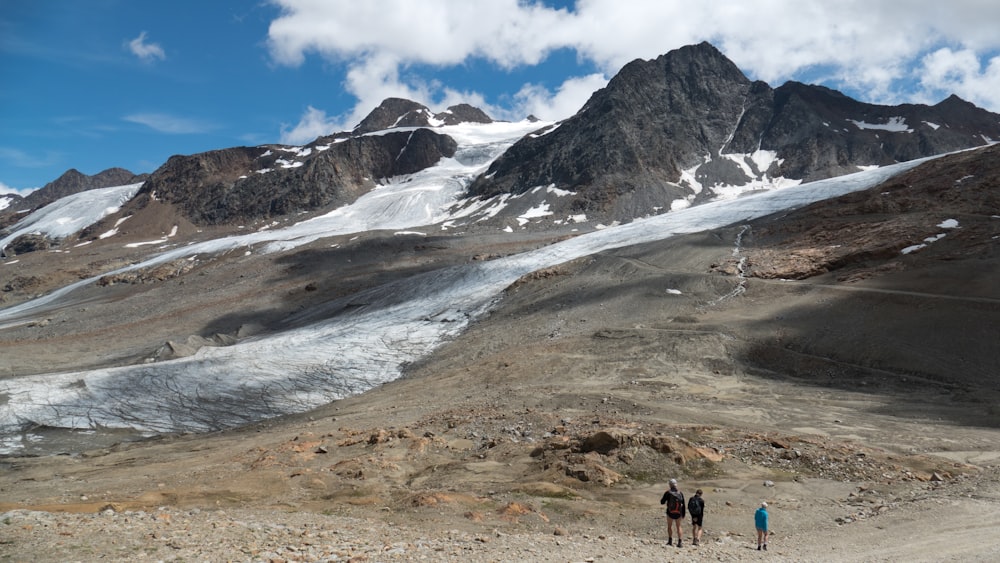 three people standing near mountain with clouds