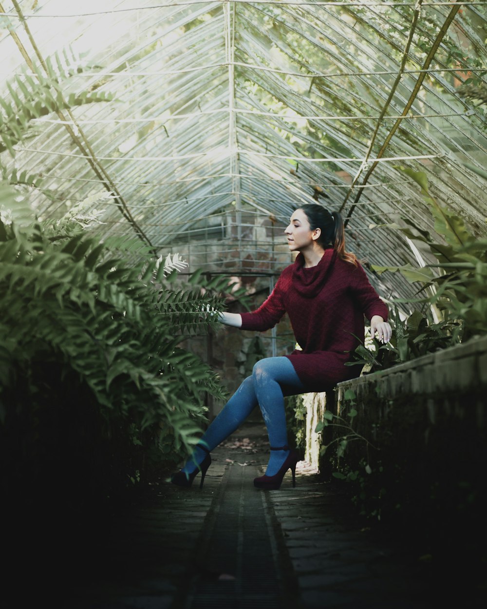 selective focus phot of woman sitting on concrete balustrade in front of plant