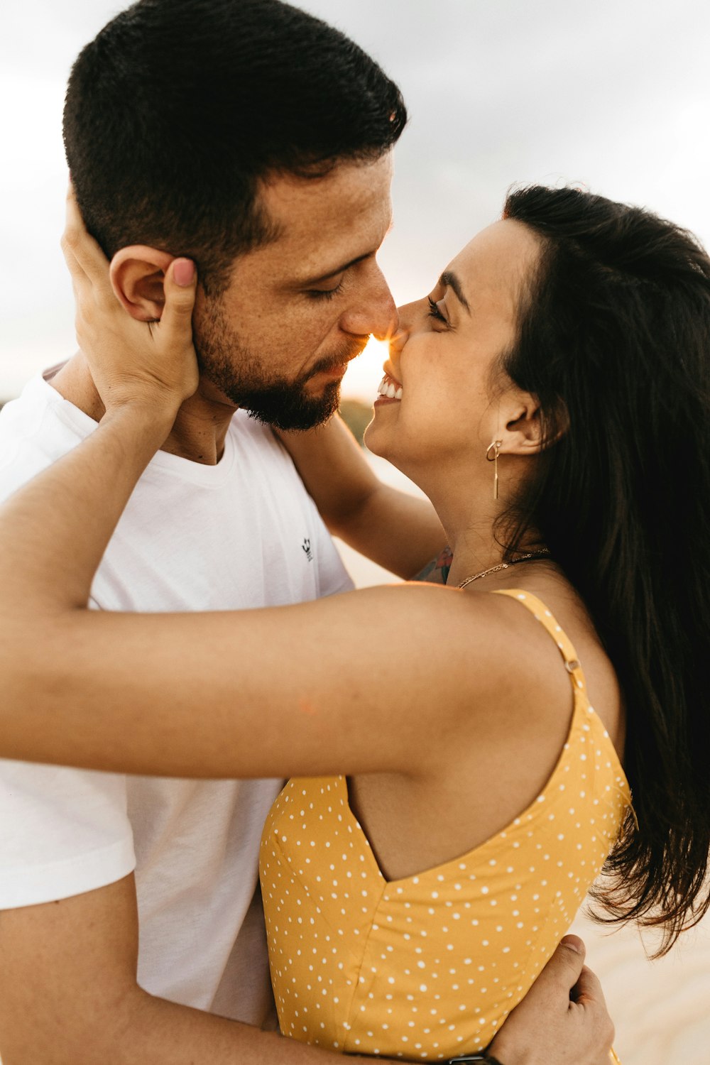 man and woman about to kiss under gray sky