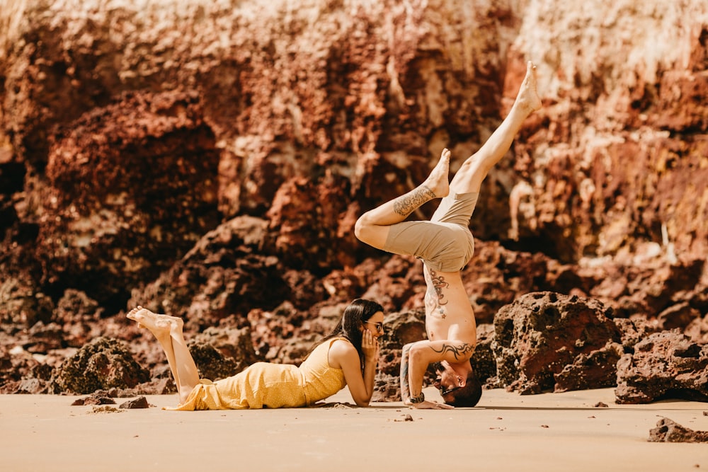 photography of woman lying on sand in front of man during daytime