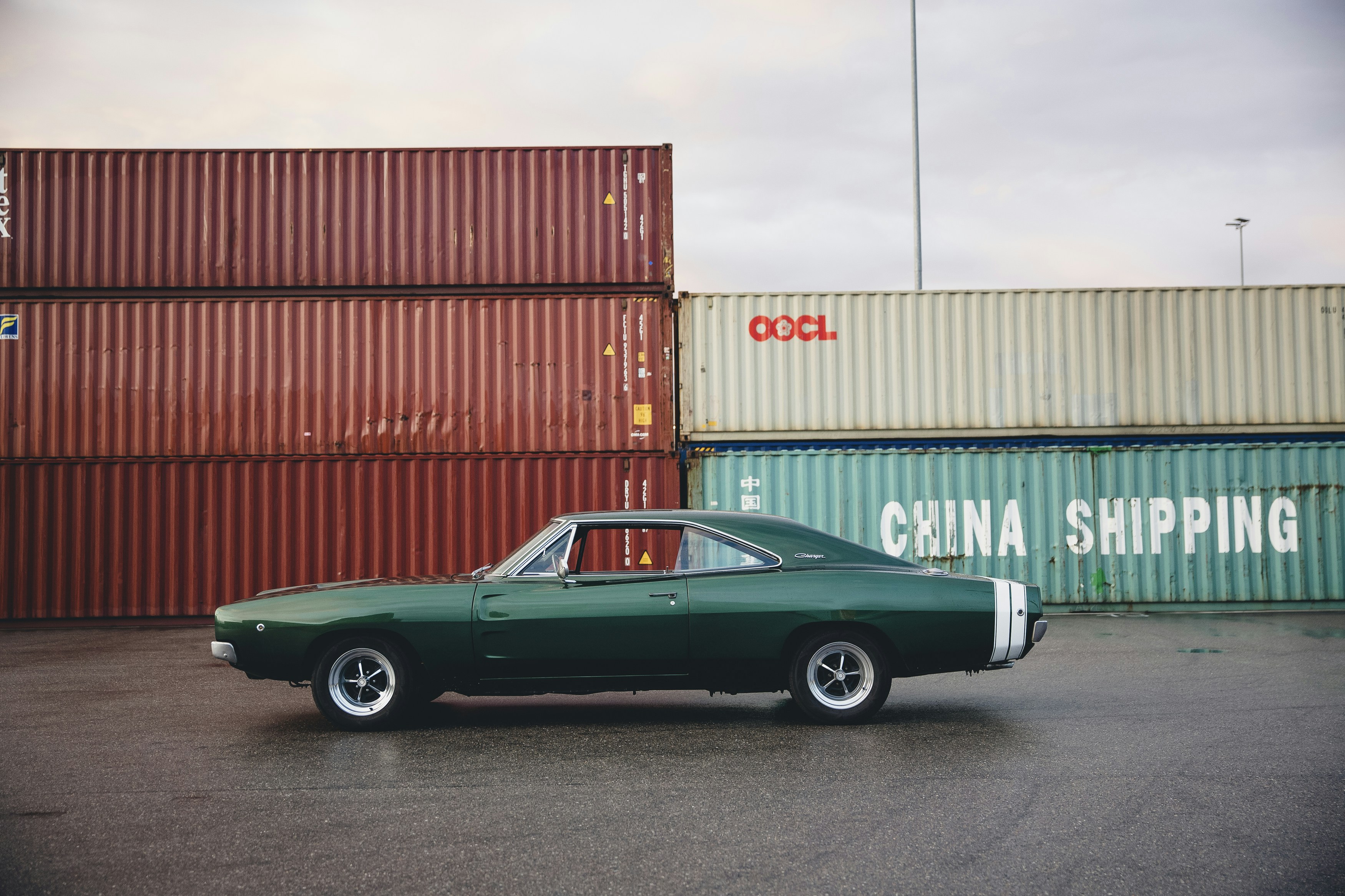 green coupe beside intermodal containers