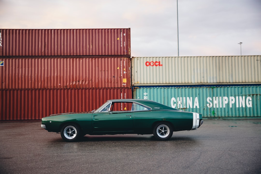 green coupe beside intermodal containers