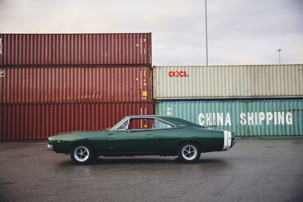 green coupe beside intermodal containers