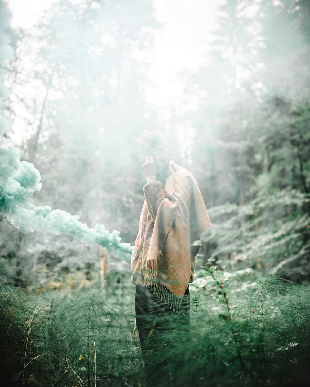 man wearing brown scarf surrounded by green leafed trees