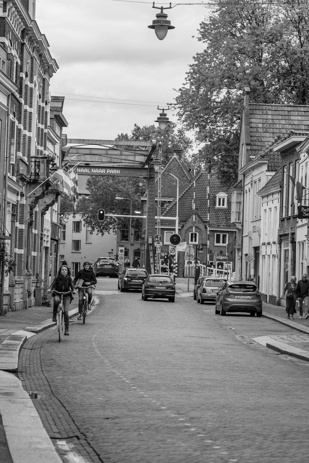 grayscale photo of people walking on sidewalk near buildings