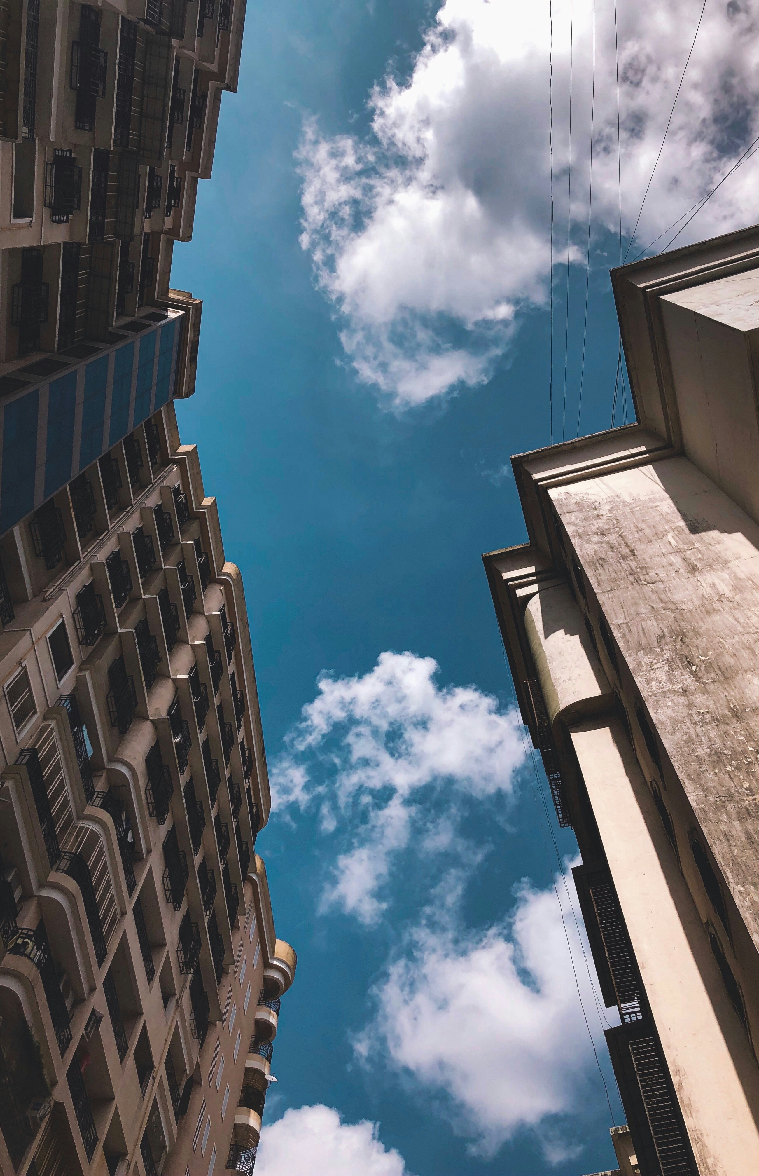 low-angle photography of gray concrete building under blue sky and white clouds