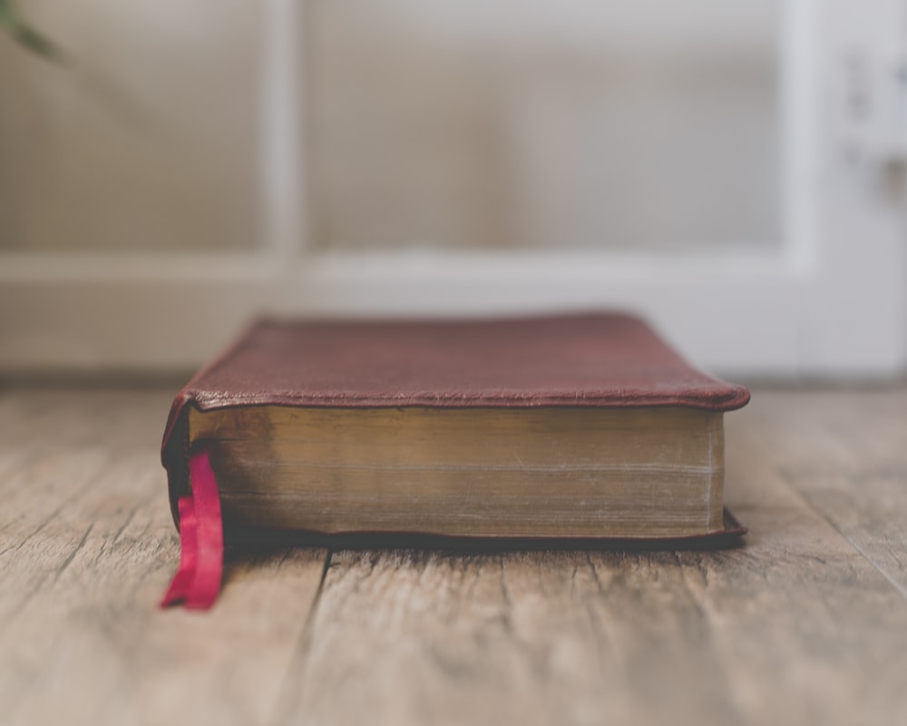 Livre rouge fermé sur une surface en bois brun