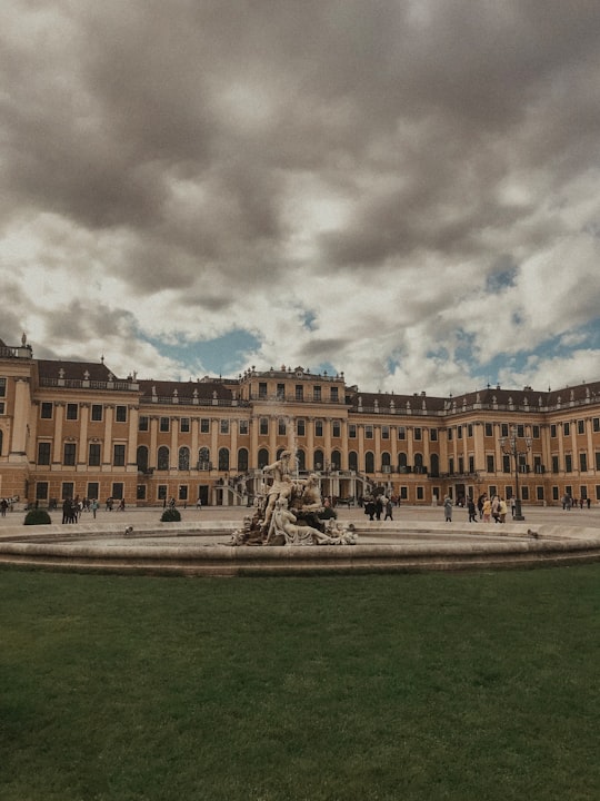 people standing and sitting near building and outdoor fountain in Schönbrunn Palace Austria