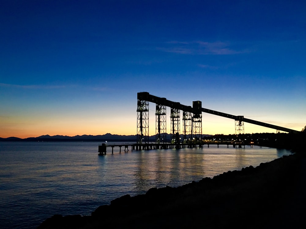 silhouette of towers and dock over water