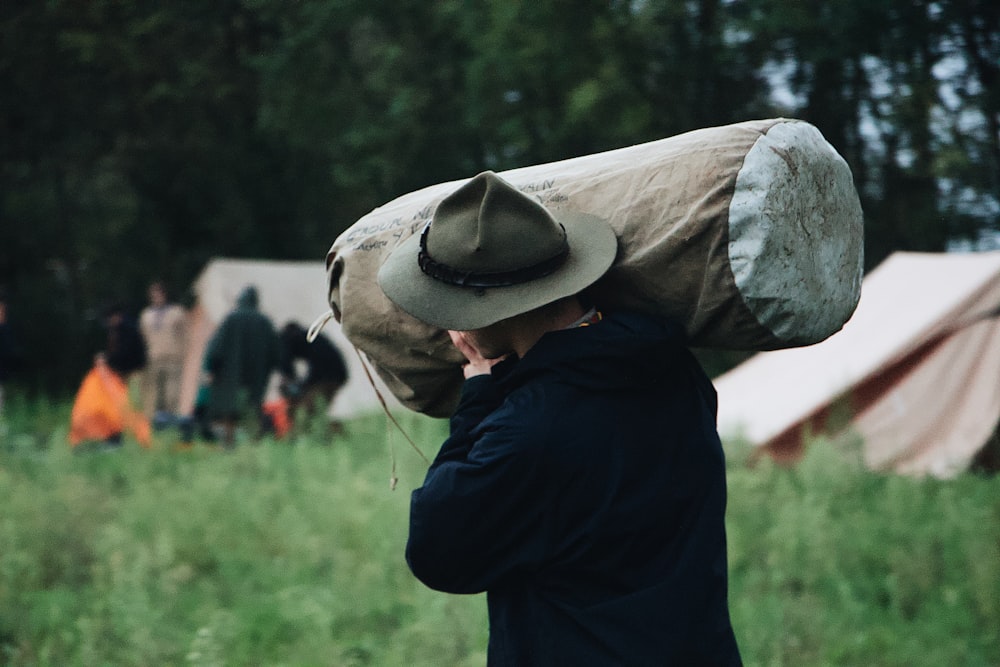 selective focus photography of walking man carrying bag near set-up tent