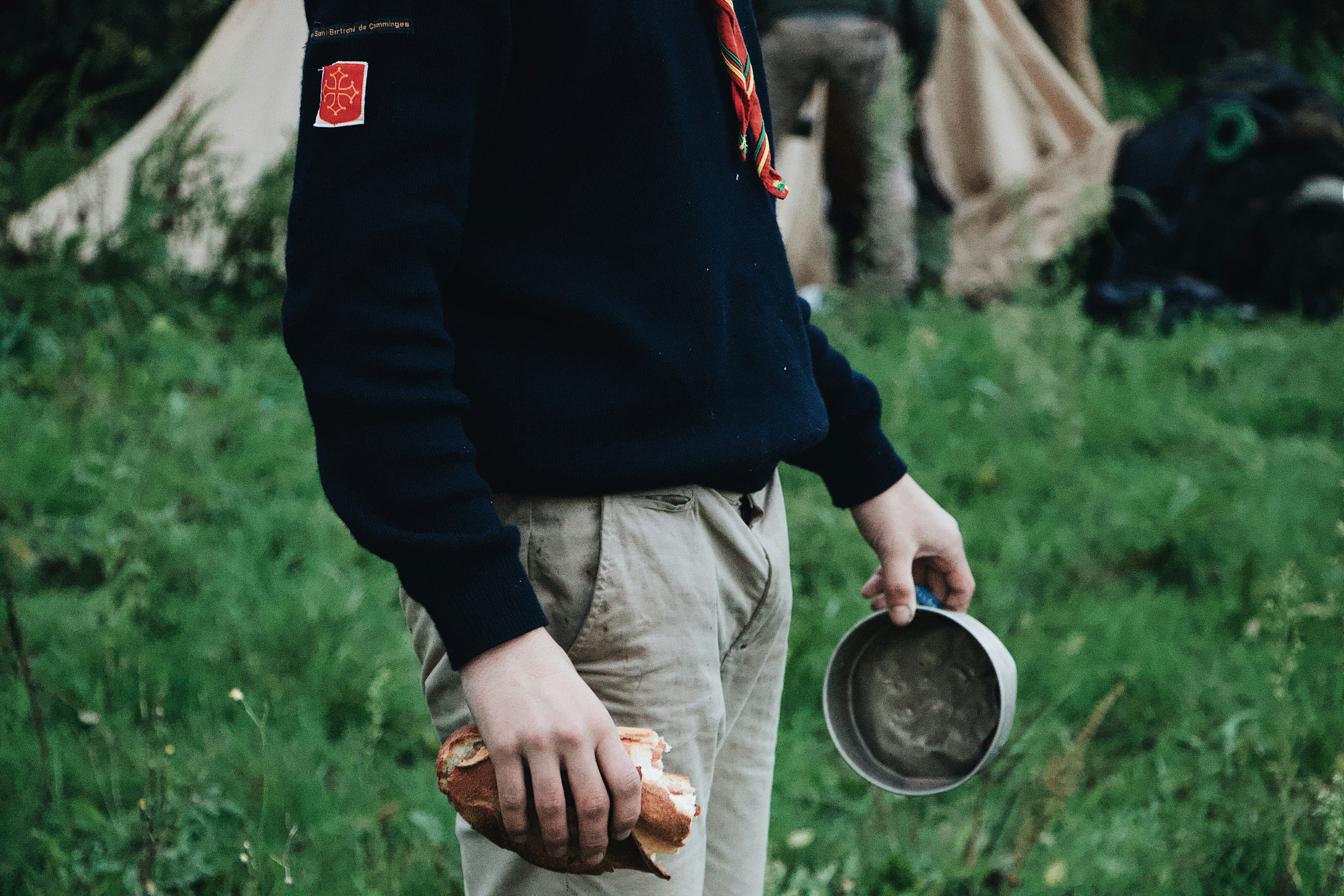 person holding bread and gray metal bowl