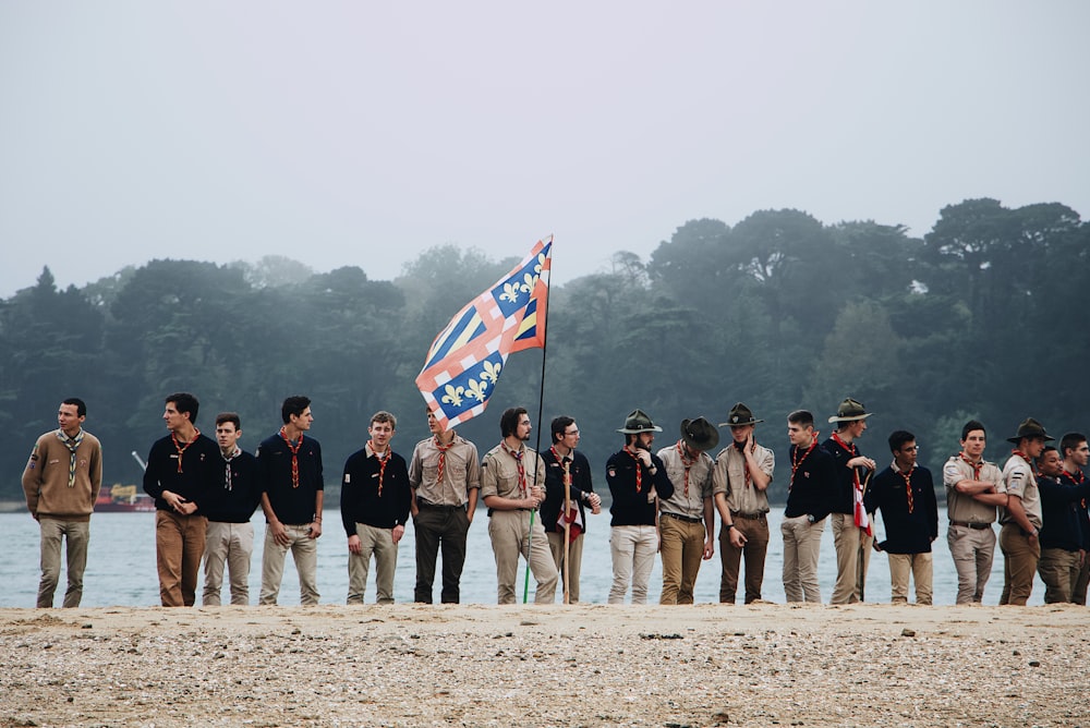 man holding white and red flag between standing men on shore during daytime