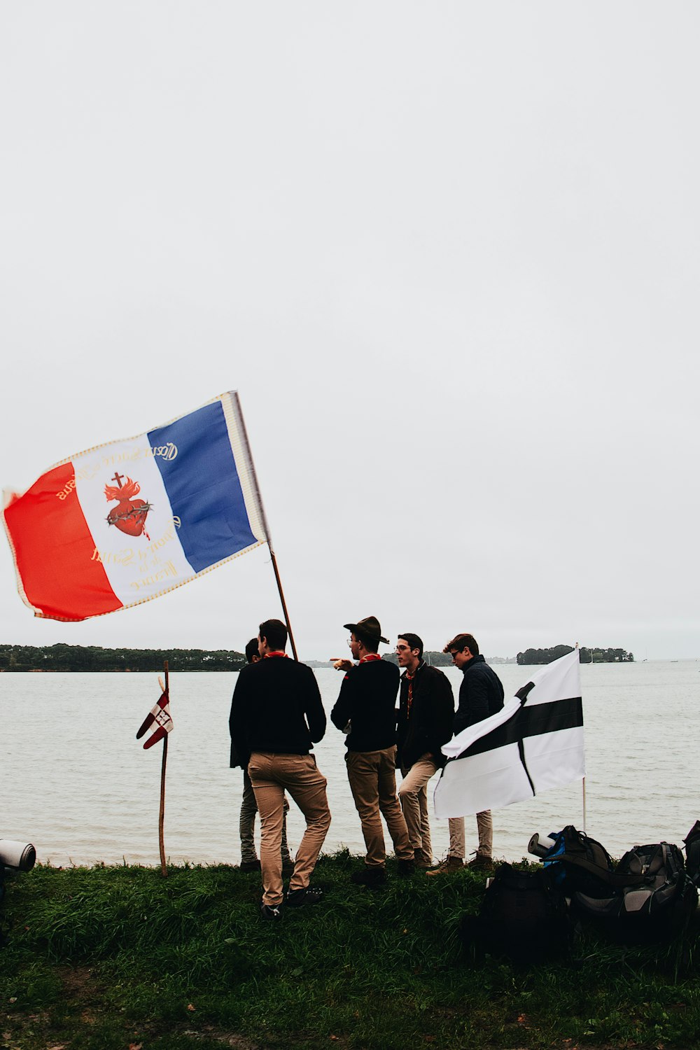 men standing beside pole with flag