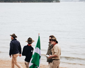 four men standing on shore near body of water