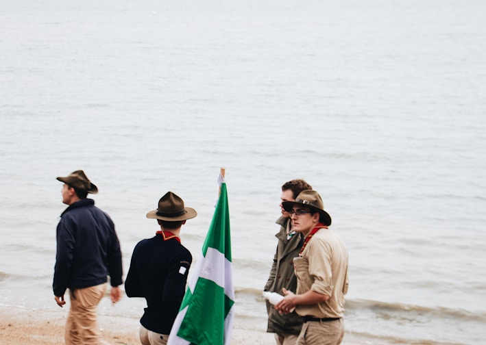 four men standing on shore near body of water