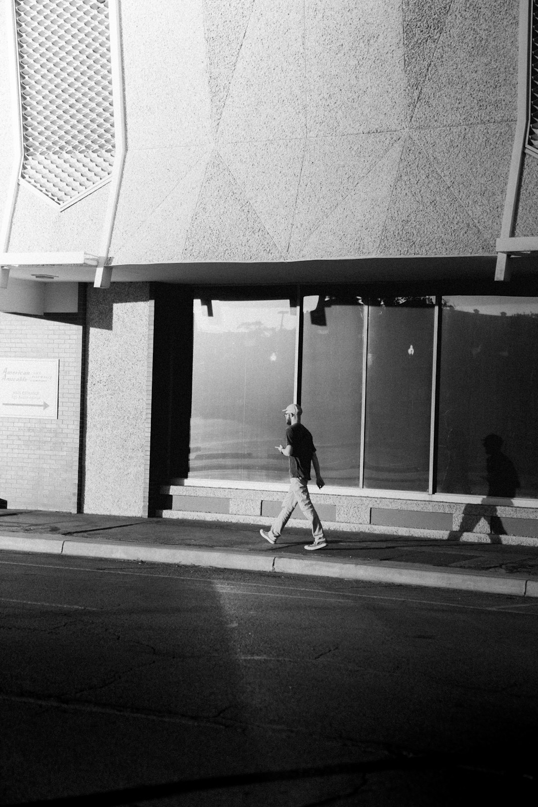 grayscale photography of man walking on sidewalk