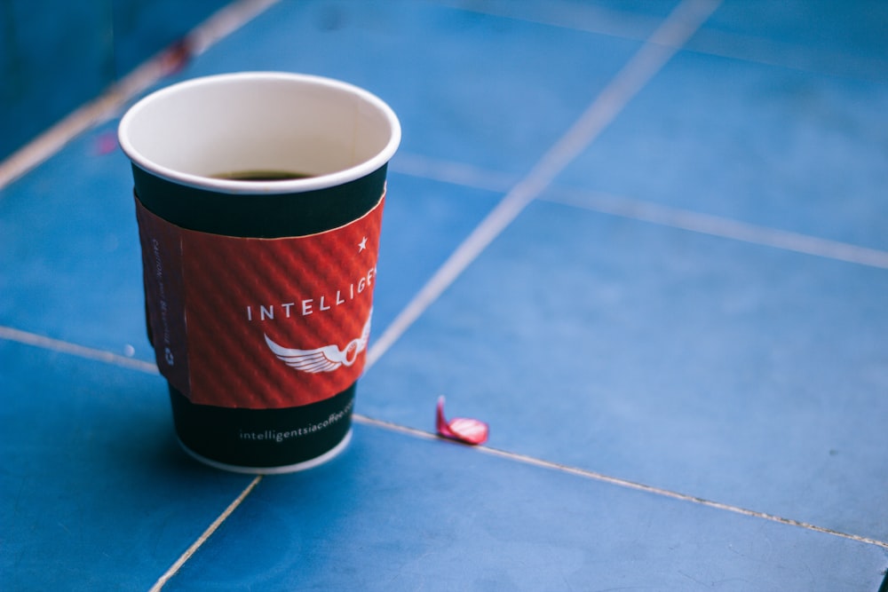 black and red disposable cup on blue surface