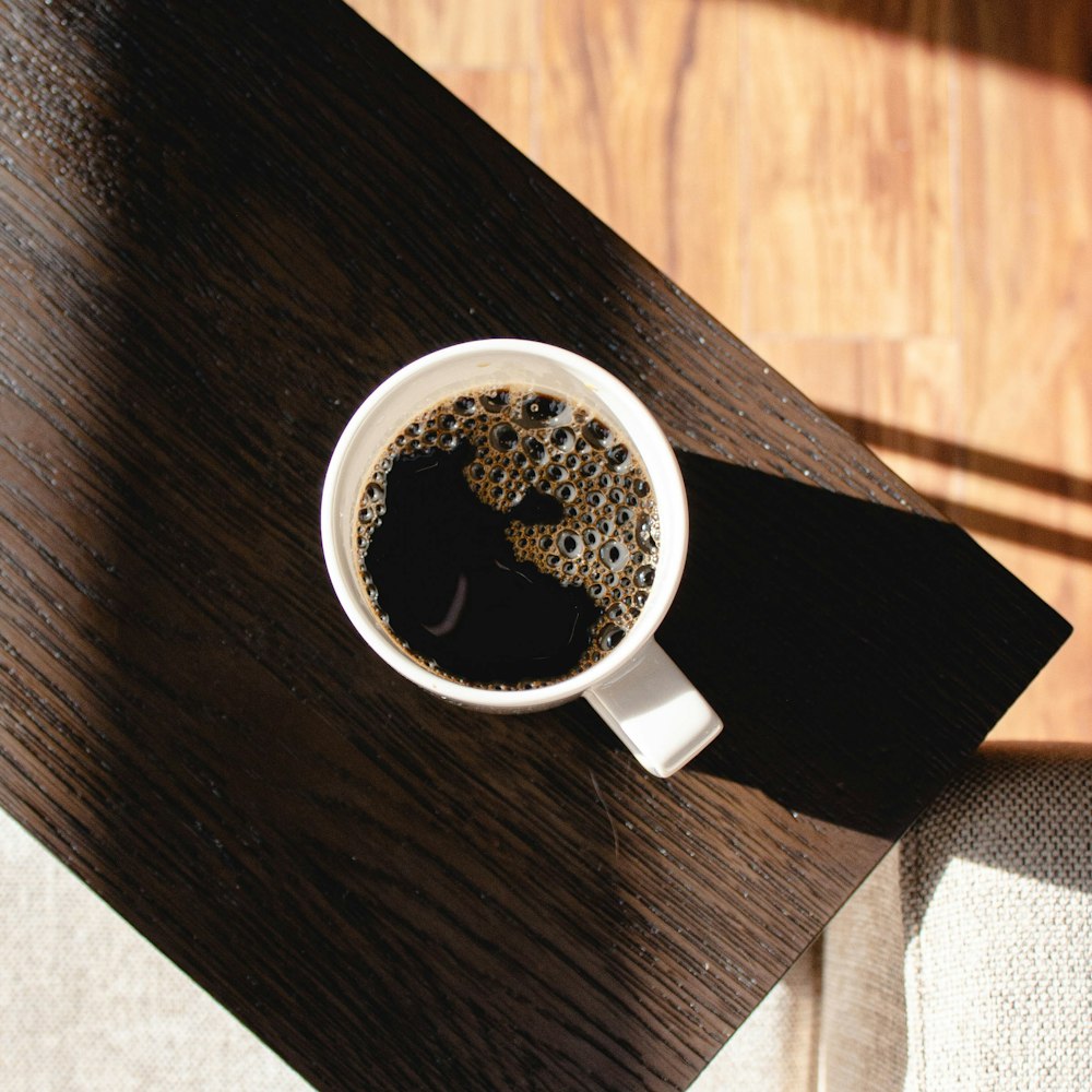 filled white mug on brown table
