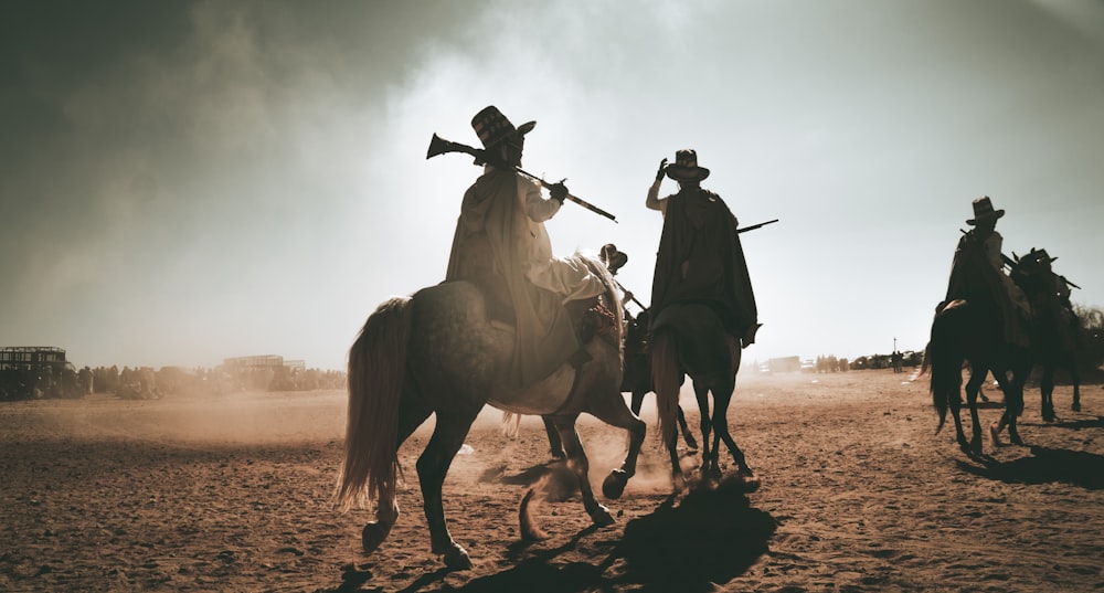 men holding rifles riding horses during daytime