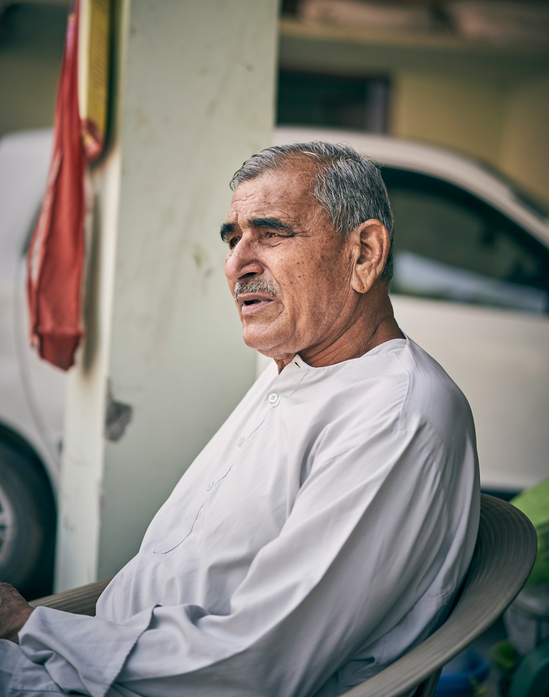 selective focus photography of sitting man in gray thobe during daytime