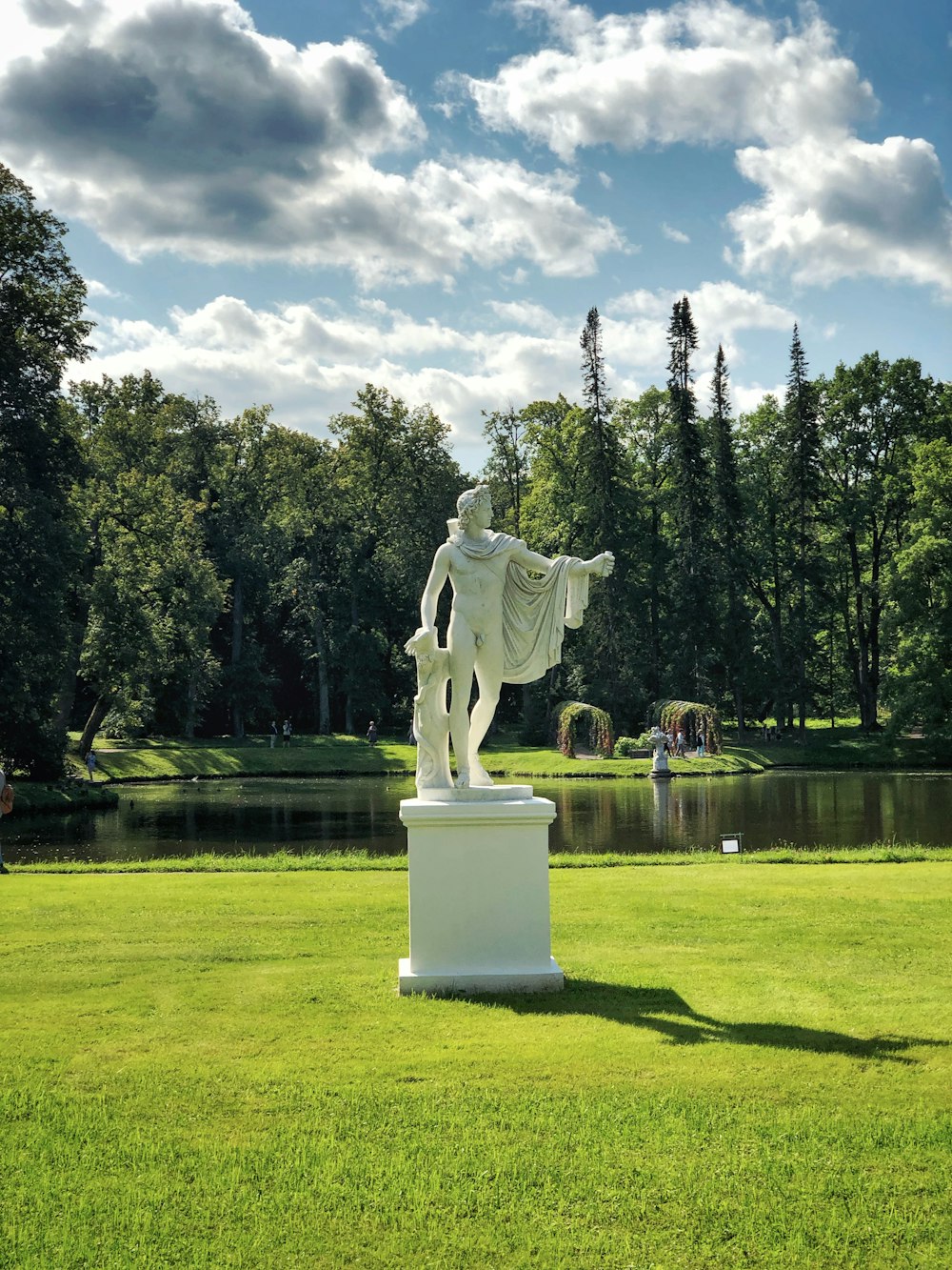 Statua dell'uomo in piedi vicino allo specchio d'acqua