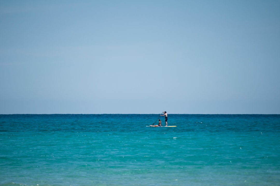 topless man riding paddle board