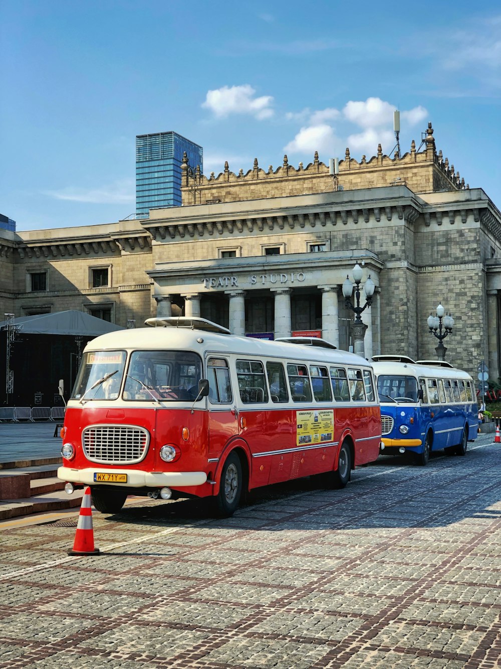 two classic blue and red buses parked near concrete structure