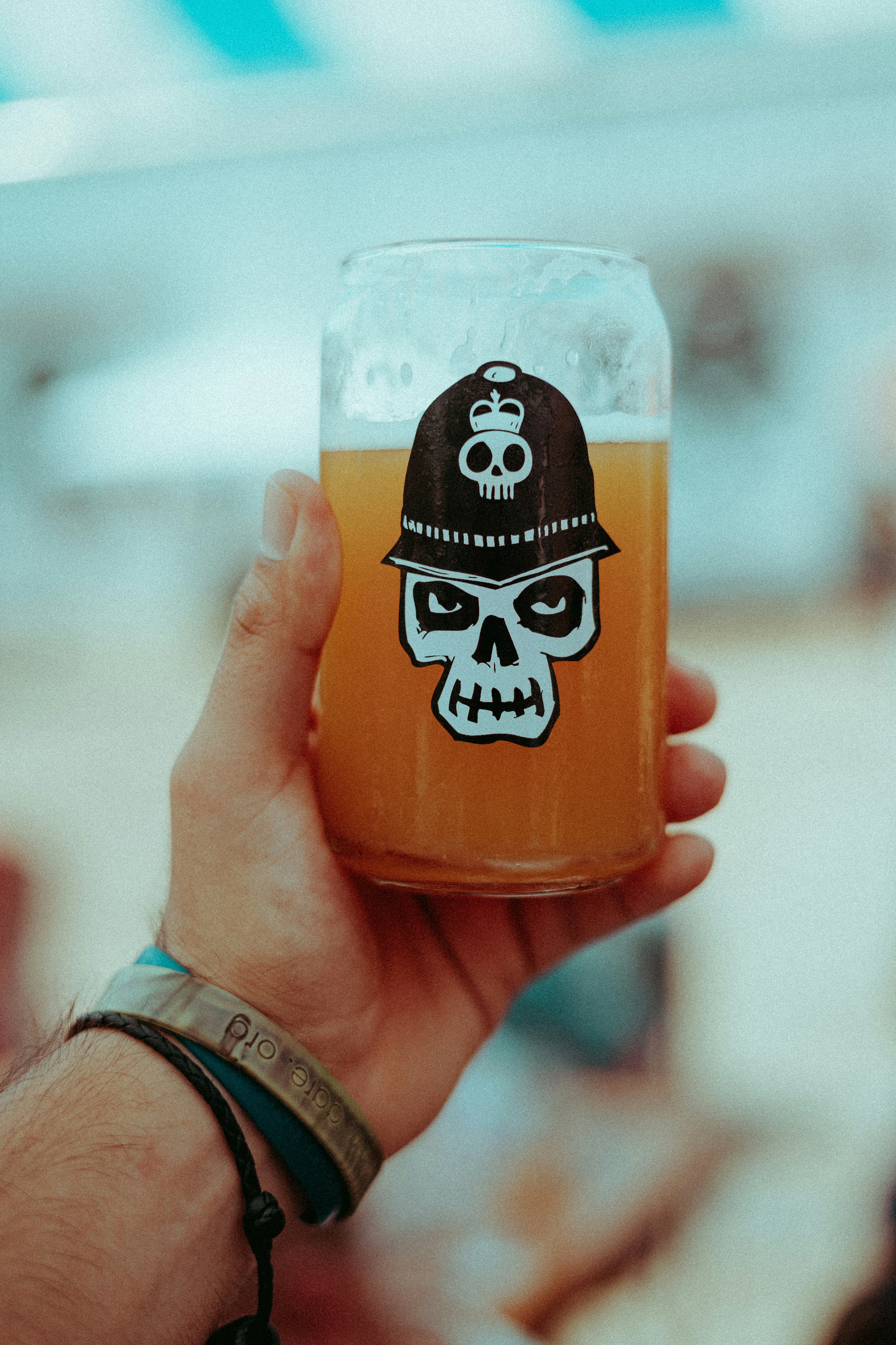 a person holding a glass of beer with a skull on it